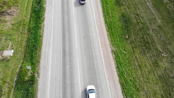 Aerial View Above Cars Driving Along Empty Countryside Road on Sunny Day