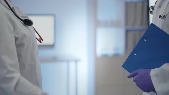 Close Up of Two Doctors in Protective Gloves Shaking Hands After Working Together in Hospital alt