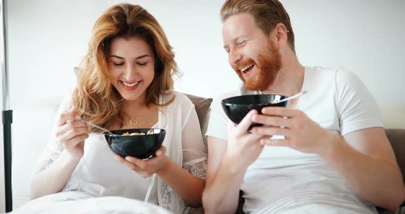 Happy Married Couple Being Romantic in Bed Sharing Cereal