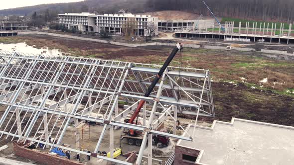Aerial Shot Installation of a Roof and a Framework From a Metal Construction, Workers Mount the Roof alt