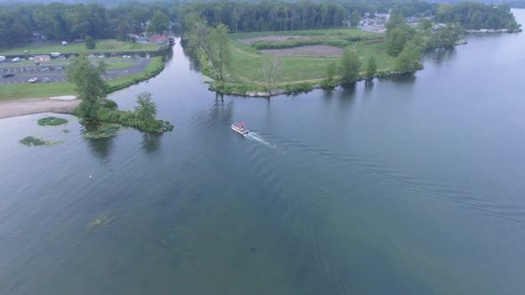 Descending drone shot of boat heading into canal to dock on Indian Lake in Ohio alt