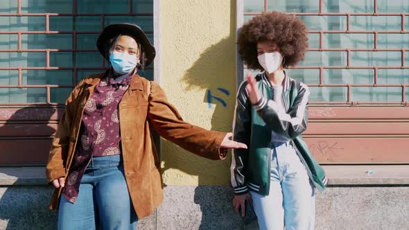 Girl friends with protective face masks giving fist bump alt