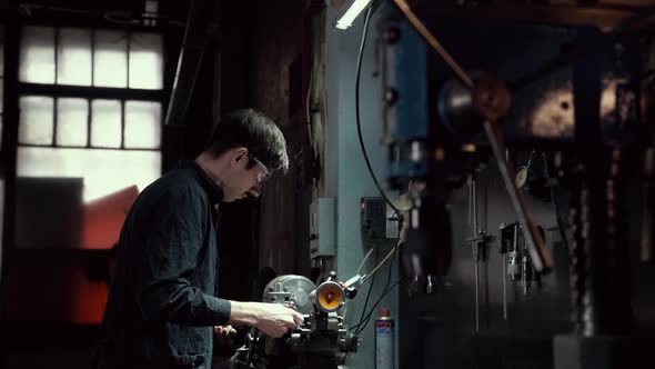 Factory Worker in Glasses Is Working a Milling Machine at Factory. The Concept of Production and