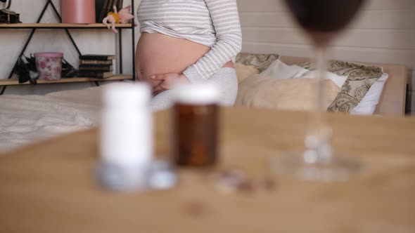Blurred Wine and Pills on the Table with a Pregnant Girl in the Background alt