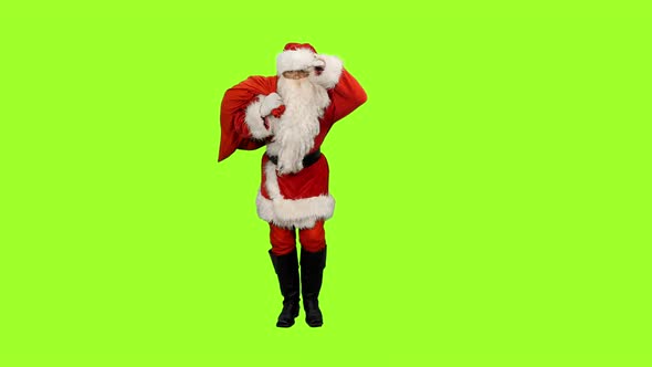 Santa Claus Goes with Gifts Bag and Looks into Distance on Green Background