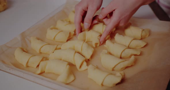Woman Making Tasty Croissants on Table in Kitchen alt