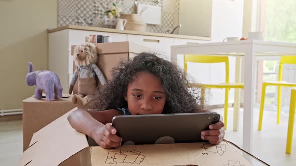 Young Girl Using Tablet Computer at Kitchen Table, Front View alt