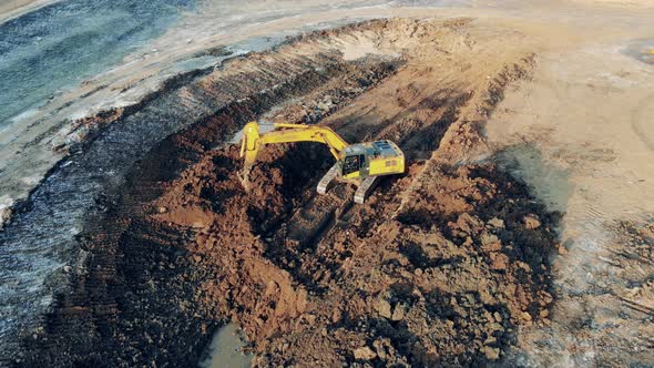 Borrow Pit with and Excavating Machine Digging Ground alt