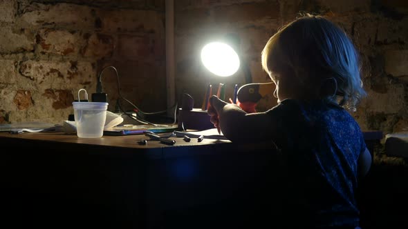 Lefty Little Girl Sits Near The Window And Painting. Baby Is Painting In The Album With Lamp Light. alt