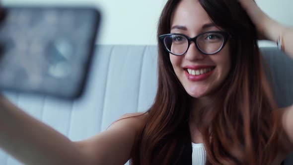 Business woman sitting at home and doing selfies on smartphone