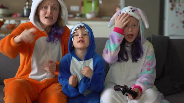 Happy Family in Kigurumi Playing a Game Console on the TV in the Living Room at Home