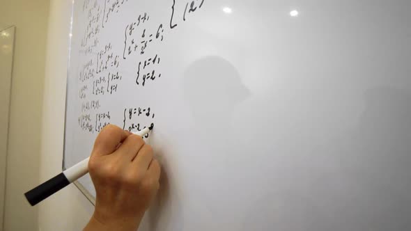 Elderly Teacher is Writing Equation on the Whiteboard