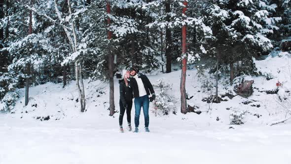 Young Couple Taking Selfies in Front of Evergreen Snow Covered Forest alt