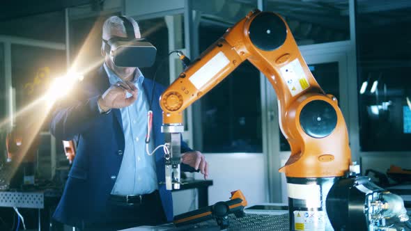 Male Scientist Is Using a VRdevice To Operate a Robot alt