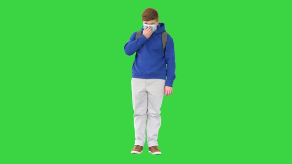 Cool Teenager Boy in Casual Clothes Wearing Medical Mask on a Green Screen, Chroma Key. alt