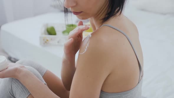 Beautiful Young Brunette Applies Cream to Her Body at Home alt