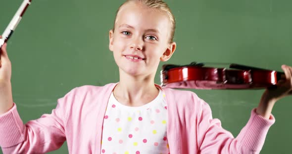Portrait of smiling schoolgirl holding violin in classroom at school alt