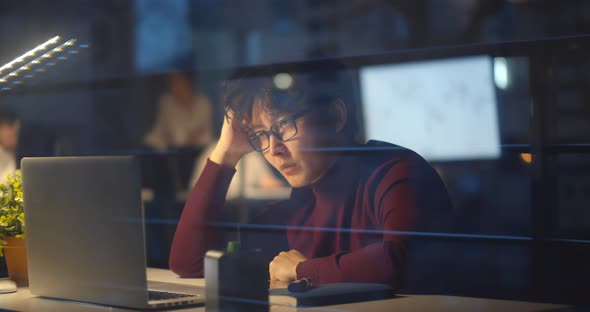 Young Businessman Having Headache Working Overtime on Laptop in Office Late Night alt