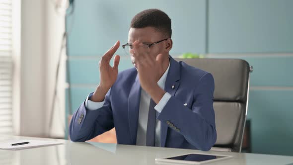 Young African Businessman with Headache Sitting in Office alt