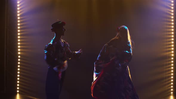Silhouette Couple Dancers in Romany Clothes Dancing Merrily in Dark Studio Against Background of alt