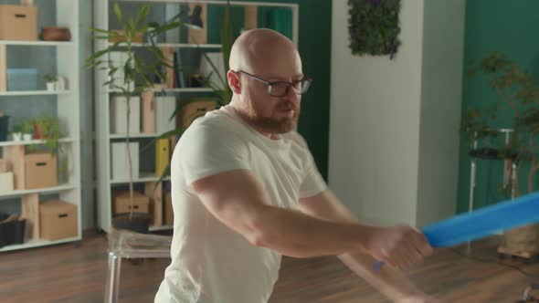 Sporty Man Doing Exercises with the Help of Fitness Expanders in the Gym alt