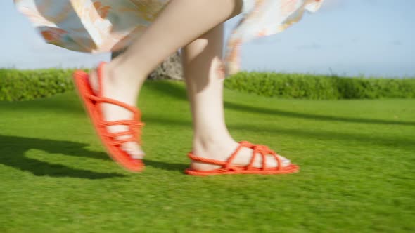 Slow Motion Woman Feet Walking in Bright Orange Red Woven Sandals By Green Lawn alt