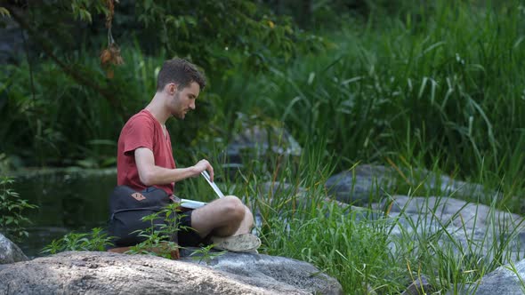 Male Hiker Working on Laptop Pc in the Wild