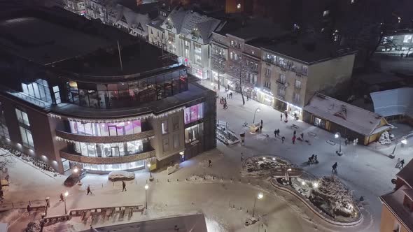 Aerial night winter scene of people walking in streets of Zakopane Krupowki district. Poland alt