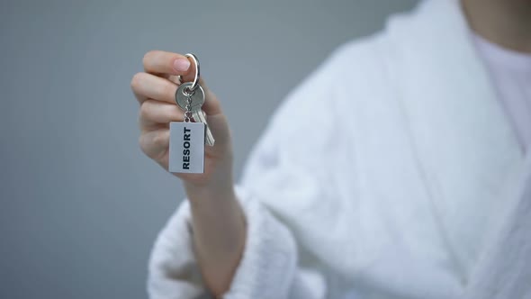 Female in Bathrobe Holding Keys With Resort Word, Spa in Hotel, All Inclusive alt