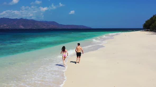Guy and girl happy together on paradise lagoon beach break by transparent water with bright sand bac alt