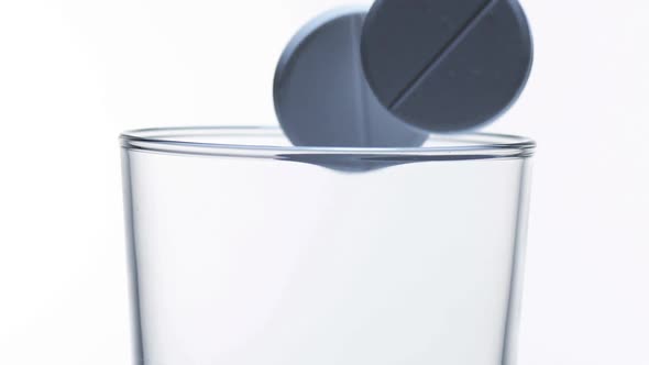 980006 Tablets Falling into a Glass against White Background, Slow Motion