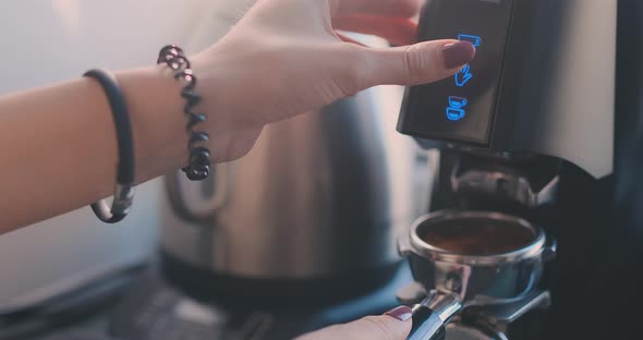 Selected Focus on the Hands of Professional Barista Pushing the Button and Holding the Handle of the alt
