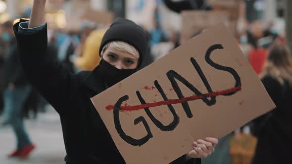 No Guns. Young Woman with Face Mask Holding Banner Against Gun Violence. Demonstration and alt