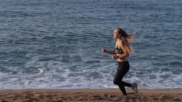 Blonde Female Runner Exercising on Sandy Beach alt