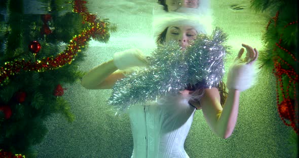 Sexy Woman in White Gown Is Whirling Underwater in Pool in Christmas, Playing with Tinsel alt
