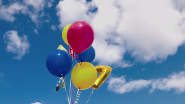 Beautiful view of festive balloons for child developing in  wind against blue sky with white clouds. alt