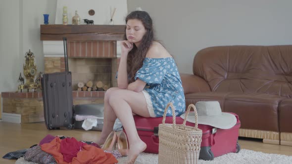Portrait Young Woman Sitting on the Suitcase and Thinking alt