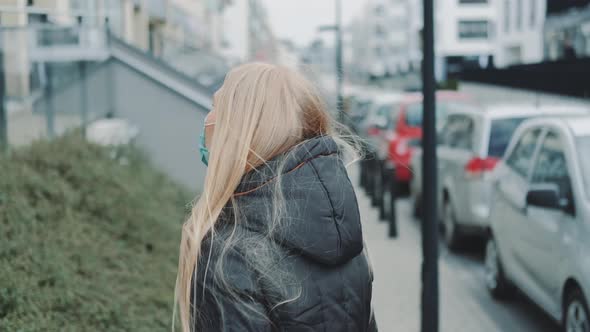 Female in a Medical Mask Escaping From Somebody on the Street. alt