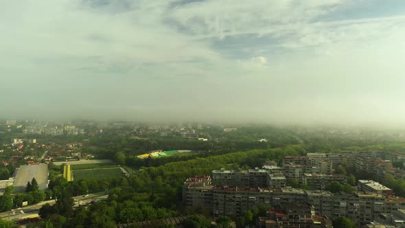 Morning Fog Raising From the City Park with a Football Stadium in the Distance alt