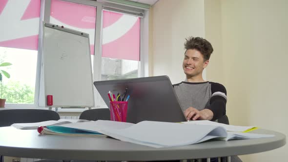 Young Male College Student Smiling, Typing on His Laptop alt