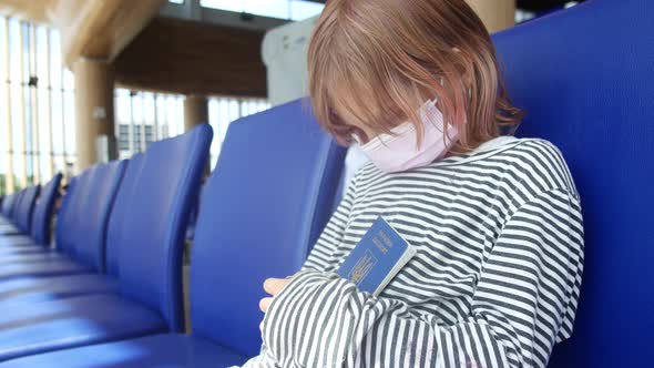 Sad Ukrainian Child Refugee at the Airport with a Passport in His Hands alt