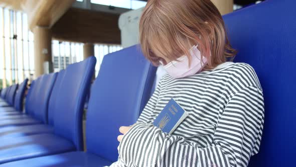 Sad Ukrainian Child Refugee at the Airport with a Passport in His Hands