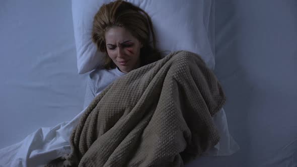 Sad Lady With Wound on Face Crying in Bed at Night Covering With Blanket, Abuse alt