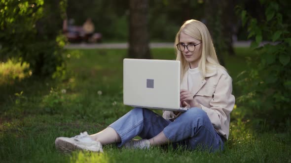 Happy Young Woman Freelancer Works for a Laptop on Fresh Green Grass
