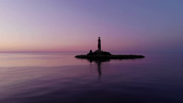 Beautiful small island with old lighthouse, scenic aerial shot at dusk
