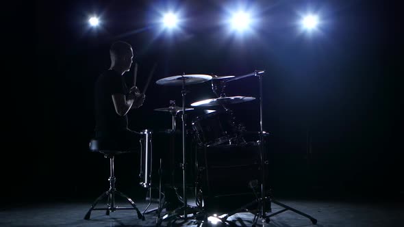 Drummer Plays the Melody on the Drums Energetically. Black Background. Back Light. Silhouette alt