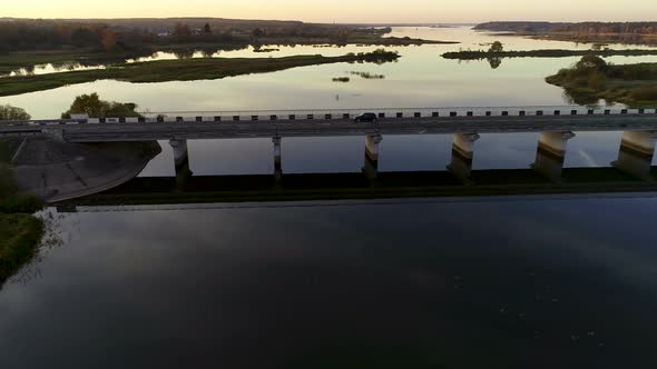 Aerial View of a Bridge Across Wide River on Sunset
