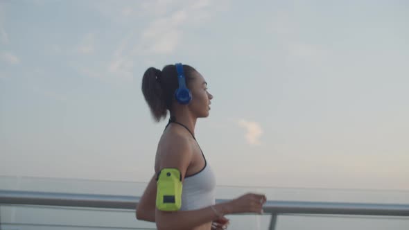 Female Runner in Headphones Jogging at Sunrise alt