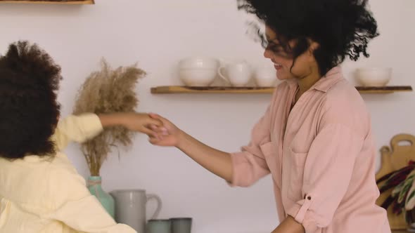 African American Woman and Girl Dancing Merrily Jumping Hand in Hand and Hugging Joyfully alt