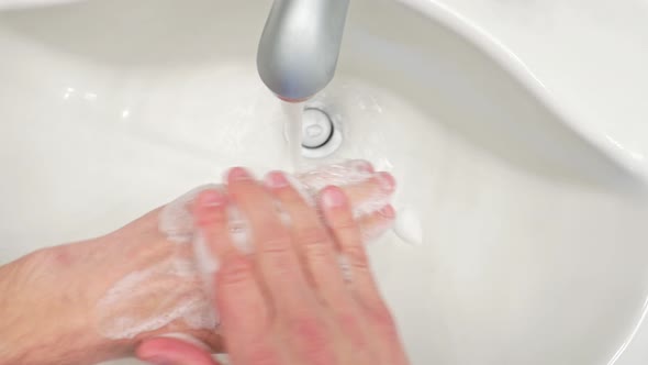 Washing hands with soap and water in bathroom 